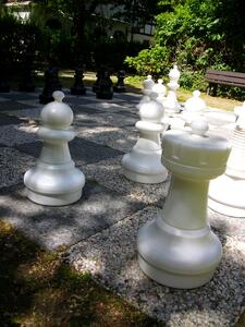 Bild vergrößern: Ansicht auf die Freischachanlage im Grünen mit zirka 1 Meter hohen Schachfiguren (hier weiße Schachgfiguren im Vordergrund). Im Hintergund eine Bank zum Verweilen.