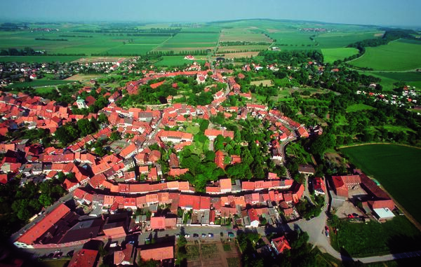 Bild vergrößern: Eine Luftaufnahme von Hornburg. Im Vordergrund die Dächer der historischen Altstadt und im Hintergrund erstrecken sich Wiesen und Felder
